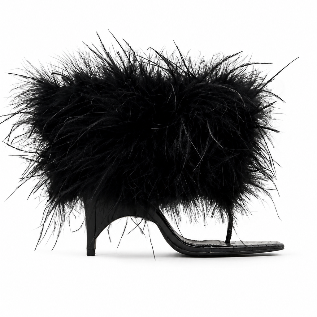 A black thong sandal with a high stiletto heel and a large, voluminous black feather embellishment on the upper, shown against a plain white background.